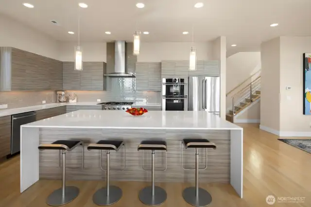 An expansive waterfall white quartz island counter invites guests to join the party while leaving plenty of space for the chef to work their magic