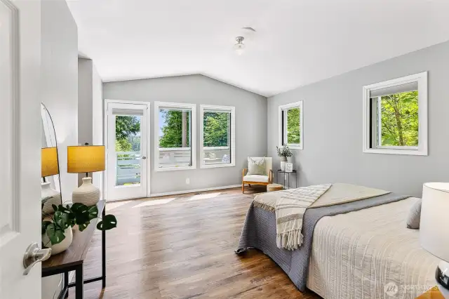 Large primary suite with pitched ceiling, southern and western facing windows, and access to a private deck. A private hallway, flanked with two generous walk-in closets, leads to a luxurious en suite bathroom complete with stand-alone soaking tub.