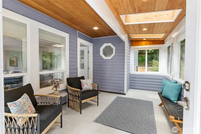 Inviting enclosed porch features warm wood accents and ample natural light, easily used as a multi-purpose space.