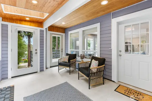 This covered porch serves as a functional hub with entry points from the driveway, the main house, and a spacious south-facing front deck that overlooks Agate Passage.