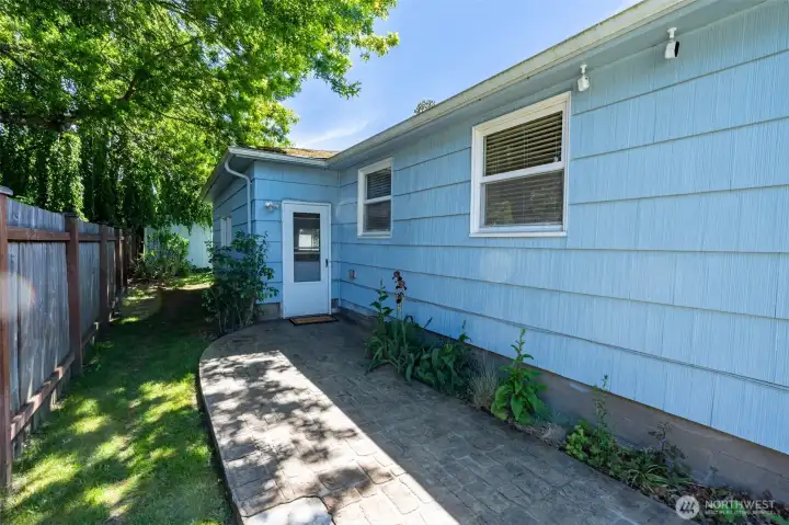Side patio off of kitchen/laundry room, connecting to extra room.
