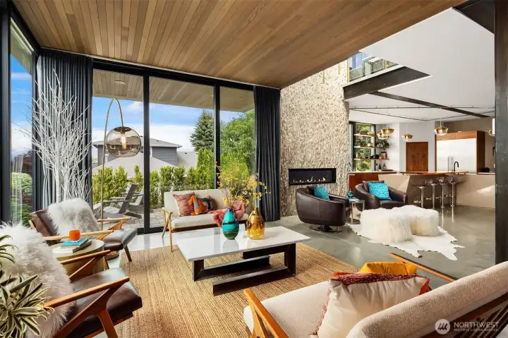 Warm and inviting living room features floor to ceiling windows and cedar lined ceiling. Stacking sliding glass doors open to a view patio