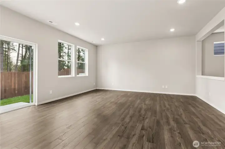 Bright great room and dining area featuring hardwood floors, neutral walls, recessed lighting, a sliding glass door to the backyard, and multiple windows for abundant natural light. Photos are representative only and may display different color packages and/or upgrades.