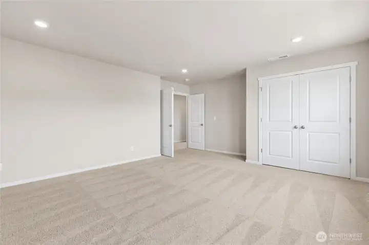 Large bedroom featuring plush carpet flooring, neutral gray walls, recessed lighting, and a large double-door closet. Photos are representative only and may display different color packages and/or upgrades.