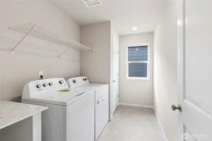 Convenient upstairs laundry room with wire shelving,  neutral walls, and a window for some natural light. Photos are representative only and may display different color packages and/or upgrades.