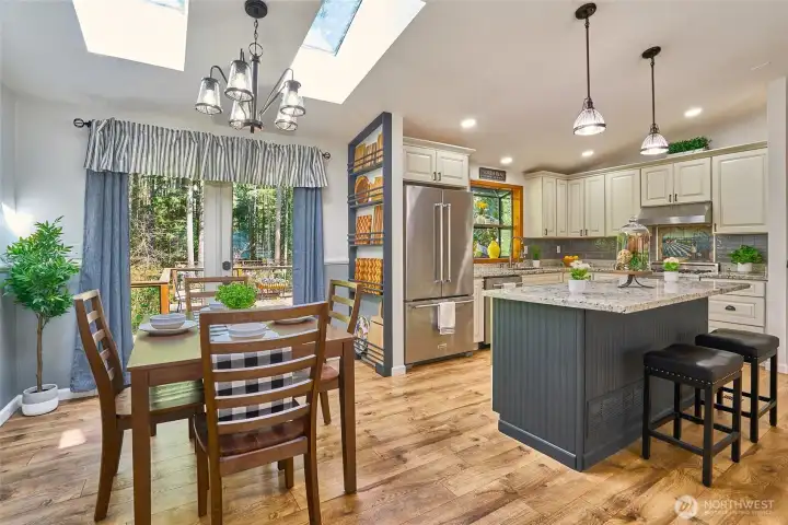 Warm and airy dining space with skylights, wood accents, chair rail and French doors opening to the expansive entertainment deck.
