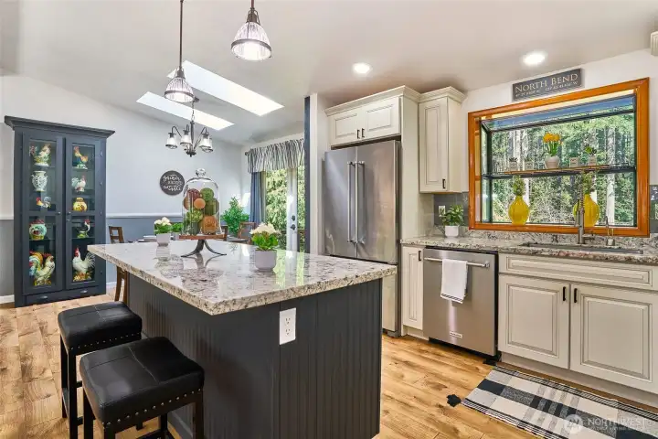 Beautifully remodeled kitchen with garden window, large island featuring pendant lighting, built-in microwave, and storage drawers, perfect for gathering.