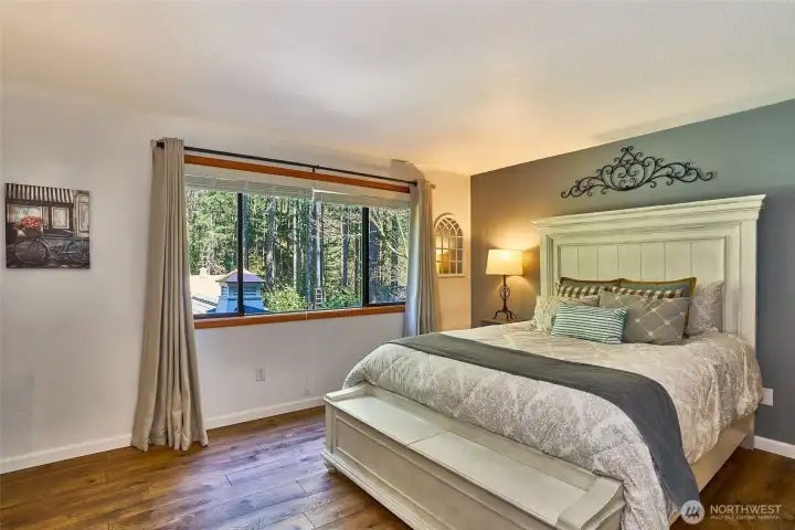Beautiful, spacious primary bedroom with peaceful views overlooking the backyard gardens and greenery.