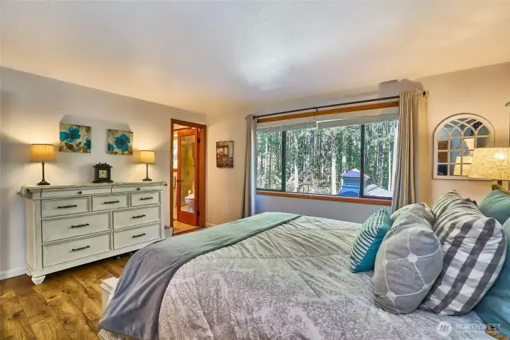 Bright and inviting primary suite angle showcasing the adjoining bathroom and sun-lit window with garden views.