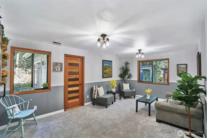 natural Light-filled lower-level family room, featuring newer wall to wall carpet, stylish wood slat doors, and convenient access to the laundry/half bath, garage, and lower-level bedroom—with easy walk-out access to the backyard.