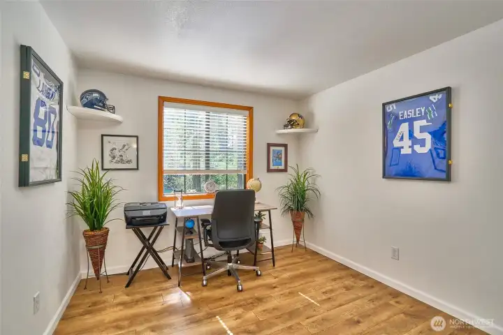 Second upstairs bedroom with laminate hardwood flooring and wood-wrapped windows. Currently used as an office, this inviting space functions perfectly as a bedroom.