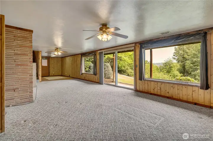 Downstairs living room with wall to wall windows overlooking lush greenery and Puyallup Valley beyond