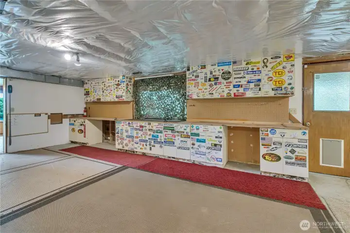 Partially finished shop space downstairs with built in work benches and cabinetry