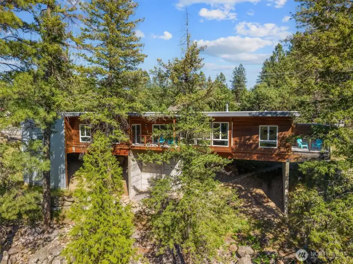 Set in one of Leavenworth's most coveted riverfront locations, this Contemporary Modern home delivers 357 feet of Wenatchee River frontage on a private lot — a rare find in this sought-after Bavarian village. Designed by Syndicate Smith and built by Hebert Construction, the 2-bed, 2-bath home with bonus room features an open floor plan, custom cabinetry by Tom Peckham, and expansive view windows. A gallery wall, TimberTech decking, and oversized 2-car garage complete the package. The primary suite opens to a private deck and hot tub. The spa-like ensuite offers a double vanity, tile shower, and heated floors. A covered main deck invites year-round river watching. Outside your door, cast a fly line on the Wenatchee River, walk next door to the golf course, and stroll to Leavenworth's restaurants, wine tasting, and boutique shops. Adventure awaits in every direction — ski Stevens Pass and Mission Ridge, wine and dine in Lake Chelan, catch a show at The Gorge, explore Wenatchee, and enjoy