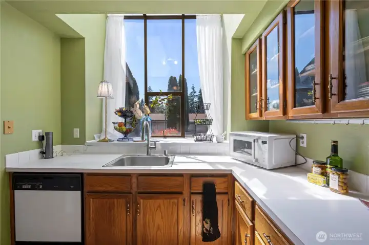 Sunny, well-appointed kitchen highlighted by a large garden-style window that brings in abundant natural light
