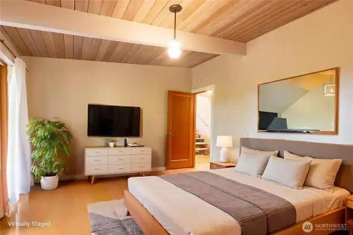 This photo has been virtually staged to help illustrate the potential of this spacious retreat. Located on the main level, the primary bedroom offers direct access to the covered deck, where sweeping territorial views provide a peaceful backdrop for morning coffee or evening relaxation. An attached ¾ bath adds comfort and privacy, creating a quiet retreat at the end of the day.
