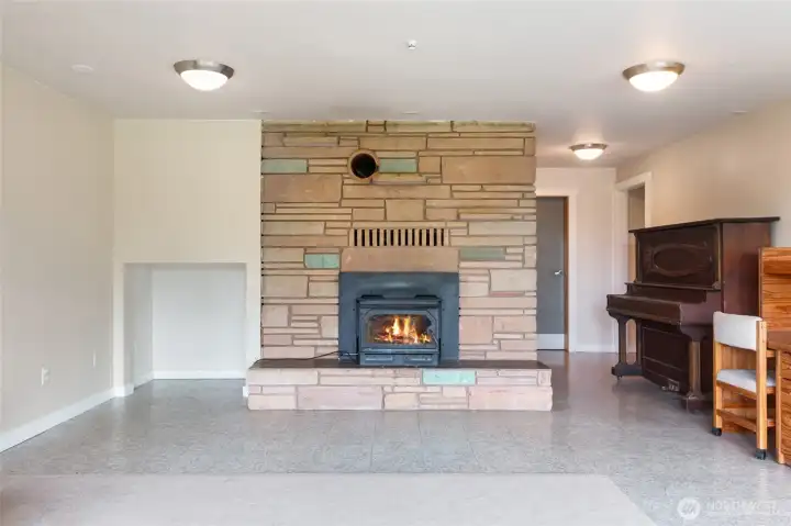A beautiful natural cut stone fireplace with a wood-burning insert serves as the focal point of the lower-level living area, adding warmth, character, and rustic charm. Beyond its inviting ambiance, the insert provides efficient supplemental heat during the winter months.