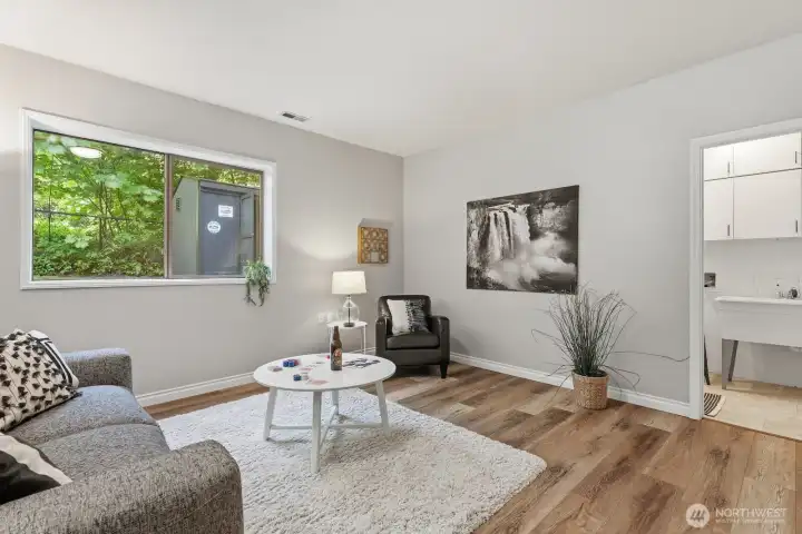 Versatile lower-level family room with luxury vinyl plank flooring and large window, offering the perfect space for entertaining or unwinding. Versatile lower-level family room with luxury vinyl plank flooring and large window, offering the perfect space for entertaining or unwinding.