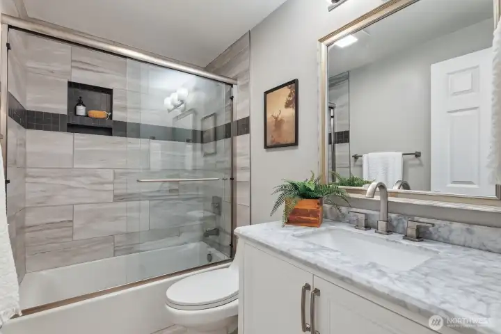 Updated full bathroom with quartz countertop, new vanity and tiled tub surround Updated full bathroom with quartz countertop, new vanity and tiled tub surround