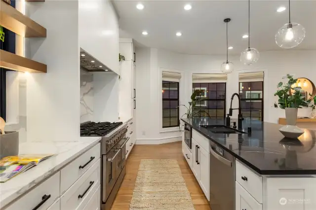 Another view of the massive island and kitchen with inconspicuous microwave and dishwasher with a seamless hood over the stove.