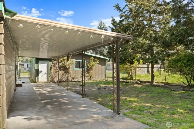 Covered patio and looking back at garage and extra storage, garden room.
