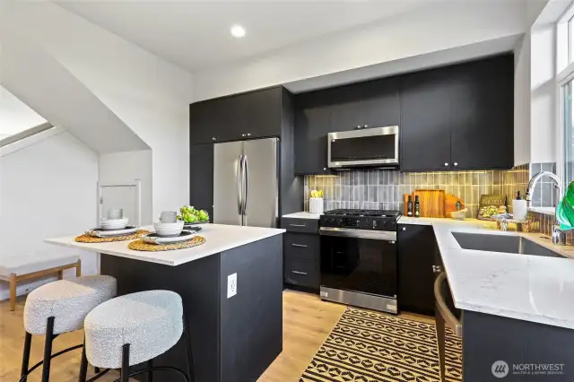 Ready to impress — this modern kitchen features a large peninsula with bar seating, gleaming quartz counters, and full-size stainless steel appliances that elevate everyday living.
