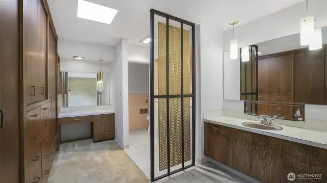Another view of the primary bathroom that showcases the built-in closets and thoughtful privacy screen.