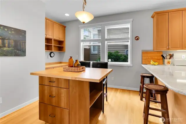 A butcher block center island with shelves and drawers below provides an additional dining area and adds lots of additional storage. There is also a built-in desk located off the kitchen, which has shelving and drawers below the desk.