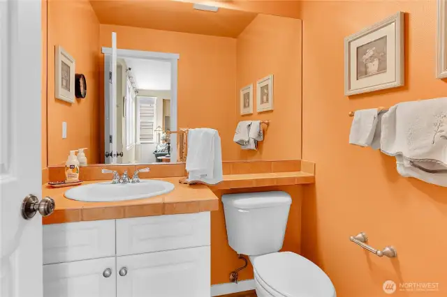 A half bath is centrally located on the main floor and features hardwood flooring and a tile top vanity counter.