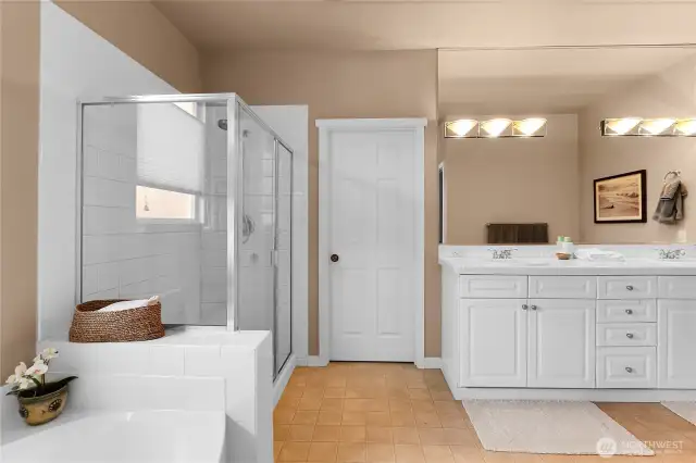 The five-piece primary bath features a relaxing corner soaking tub with a big window above, plus a glass enclosed shower.  The vanity counter is extra tall and has two sinks for the ease of multiple users.  The toilet is located in a separate room off the primary bath, for privacy.  A walk-in closet is also located off the primary bath and will accommodate extensive wardrobes.
