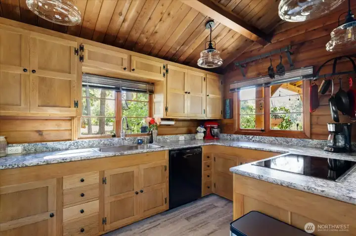 Brushed granite countertops, gorgeous custom wood cabinets, new flooring, and lots of windows.  Notice to the new lighting fixtures!  The pot racks and appliances all stay.