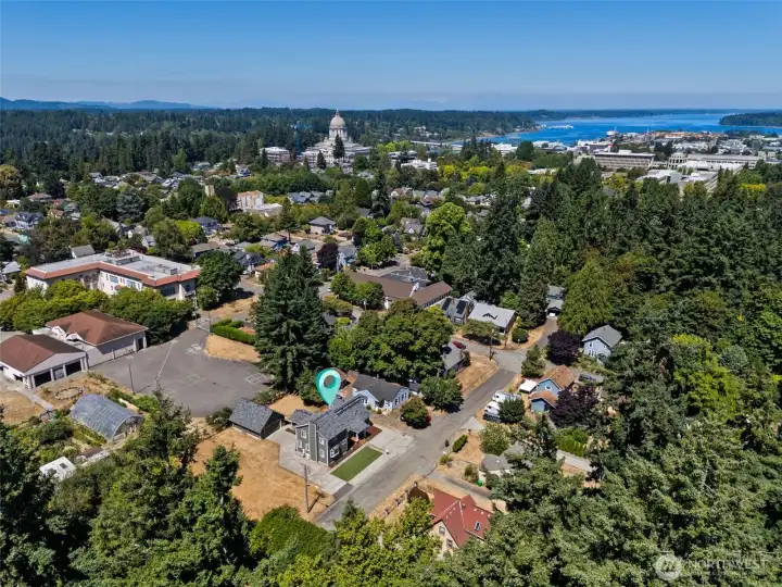 This aerial shot shows the perfect location just a block away from two local gems. Olympia Baking Company, a gluten-free bakery known for its scones and savory treats, is just a short stroll away. Similarly, Frog Pond Grocery, with its iconic green-painted facade and giant frog sign, is a food lover’s paradise offering everything from locally sourced produce to artisanal cheeses and organic meats. It’s a neighborhood that offers convenience and delicious options right around the corner.