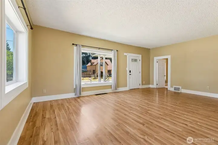 Unit A’s living room is a perfect blend of warmth and charm. The warm wood laminate flooring pairs beautifully with neutral tone walls and wide vintage white baseboards, creating an inviting and timeless atmosphere. With plenty of windows that bring in natural light, this room feels bright and airy. It also serves as the main entry to the home, making a great first impression as you step inside.