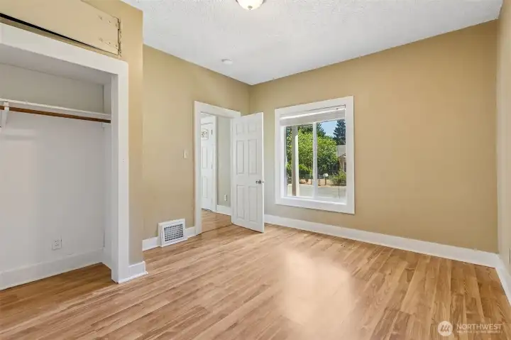 Unit A Bedroom #2 is all about versatility and charm. With pass-thru access to both the den and living room, it seamlessly flows into the rest of the home. A cute built-in shelving area adds a touch of character as you move into the den. The warm wood-tone laminate flooring and the huge picture window bring in natural light, making this room feel bright and inviting.