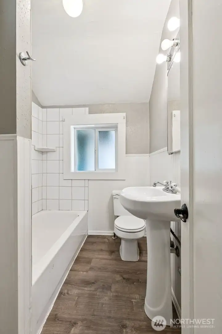 Unit A’s full main floor bathroom is all about timeless charm. The classic pillar sink adds elegance, while the tub with a tile shower surround creates a relaxing retreat. A window that opens with privacy glass allows natural light without compromising privacy. It’s a bathroom that feels welcoming and practical.