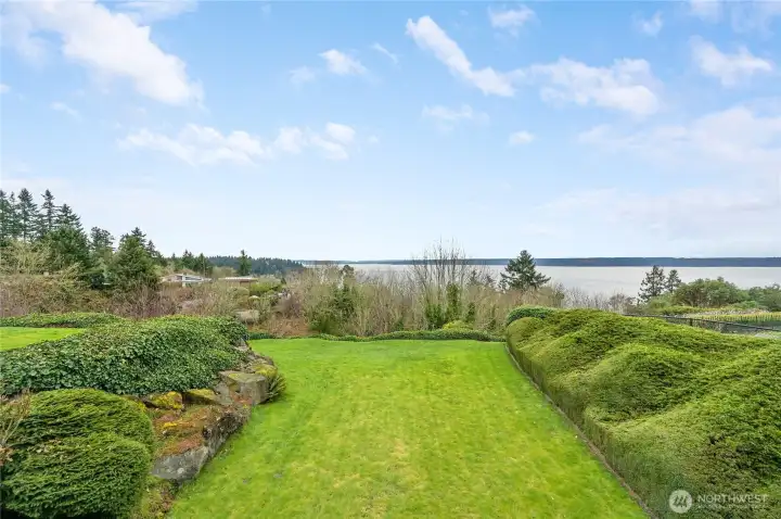 Expansive bluff-top lawn framed by sculpted hedges and natural stone, opening to sweeping water views. A serene, private setting perfect for relaxing or entertaining while enjoying the ever-changing scenery.