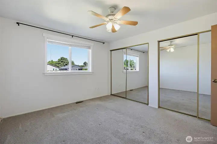 Primary Suite with double mirrored door closets and ceiling fan.