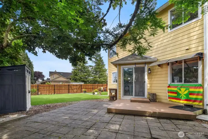 Backyard patio off kitchen shaded by trees.
