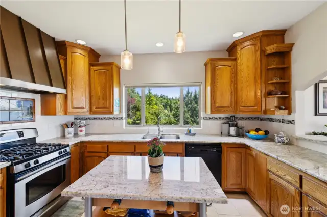 There is a water view from the kitchen window and a pass-through on the right side. The slab Granite countertops match the Island and continue in the Butler's Pantry area behind this photo.