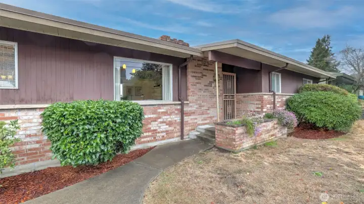 A welcoming front entry framed by mature landscaping and timeless brick accents.
