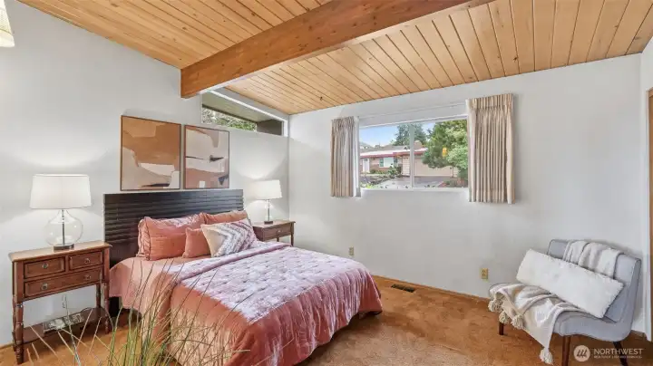 Retreat to this peaceful primary bedroom with warm wood ceilings and soft natural light.