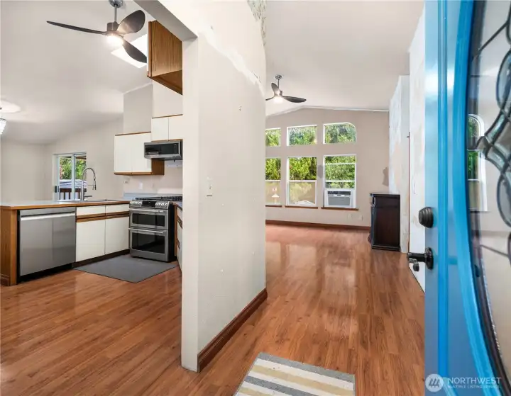Welcome to this open-concept main living space with warm wood floors, vaulted ceilings, and a kitchen featuring stainless steel appliances including a double oven, gas range and a farmhouse sink.