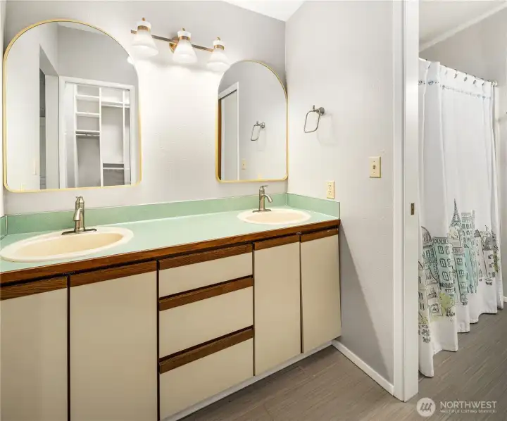 Double-sink master bathroom vanity with dual mirrors, and adjacent primary closet boasting an installed organizational California Closet.