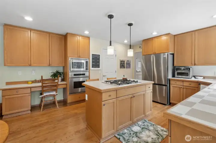 Let's check out the kitchen with new fridge, gas cooktop in the island, hardwoods, pendant lights and oven/microwave.