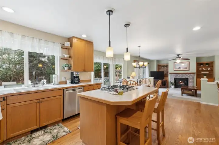 A view showing the kitchen island with seating, large window over the sink, and more of the family room.