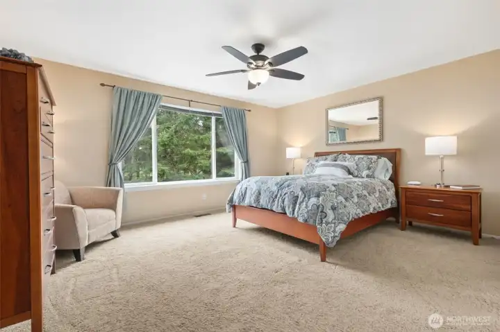 As we move upstairs, this is the primary suite - you enter with double doors and it features a ceiling fan, large window, and the 5 piece primary bath just to the right.