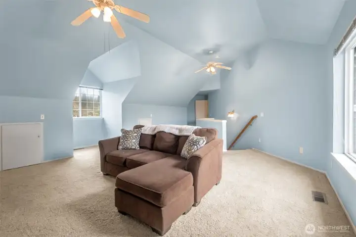 GINORMOUS bonus room with storage - ceiling fans and that's the second stairwell behind the small wall with the railing.