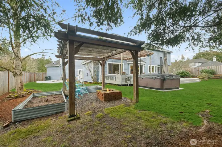 Sellers have a firepit and garden bed in the corner of the yard under another pergola.