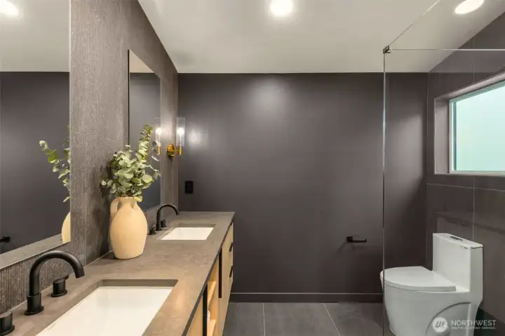 The primary bath features luxury floor to ceiling textured tiling, floating cabinetry. Luxury glass shower with rainfall showerhead for a true spa-like wetroom.