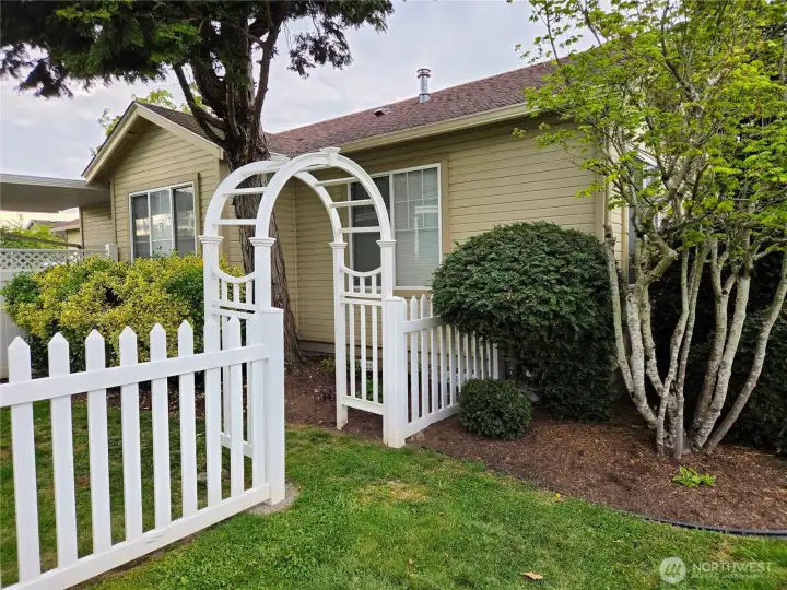 Storybook charm begins with the arbor and picket fence leading into the backyard.